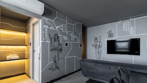 Moderni hotellin aula, jossa on suuri seinämaalaus, litteänäyttöinen televisio ja oleskelualue.