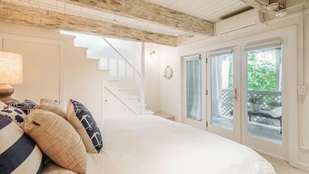 Un dormitorio con una cama, una lámpara y una escalera que lleva a un balcón.