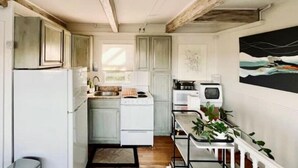 Una cocina pequeña con gabinetes blancos, un horno y un lavabo.