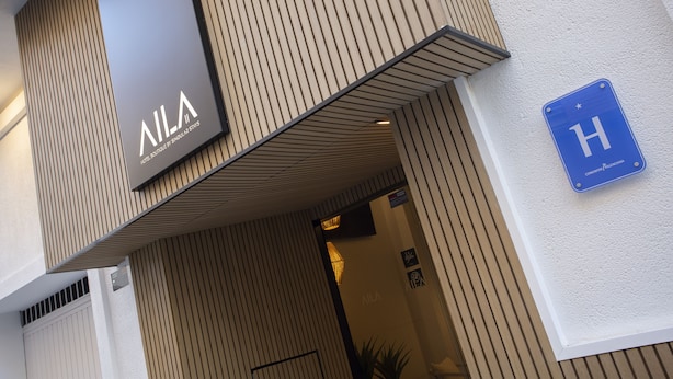 Entrada de un hotel con un cartel que dice "VILA HOTEL" y una señal azul que indica hotel.