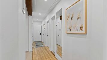 Un couloir aux murs blancs, au plancher en bois et aux œuvres d’art encadrées.