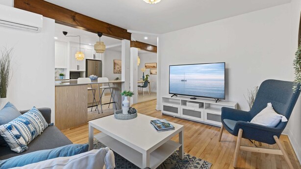 A modern living room with a flat-screen TV, a blue armchair, and a white coffee table. - All-Inclusive Furnished Large 2BR Apartment in Rosemont (Montréal)