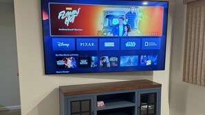 A flat-screen TV mounted on a wall with a dark wooden entertainment center below it.