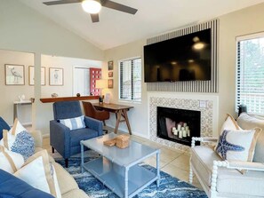 Una sala de estar con televisor, chimenea y zona de estar.