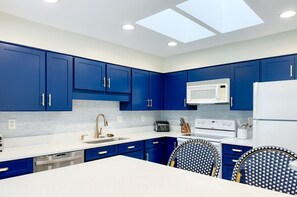 Una cocina moderna con armarios azules, electrodomésticos blancos y un tragaluz.