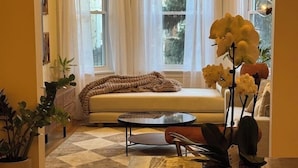 A cozy living room with a sofa, a coffee table, and a potted orchid.