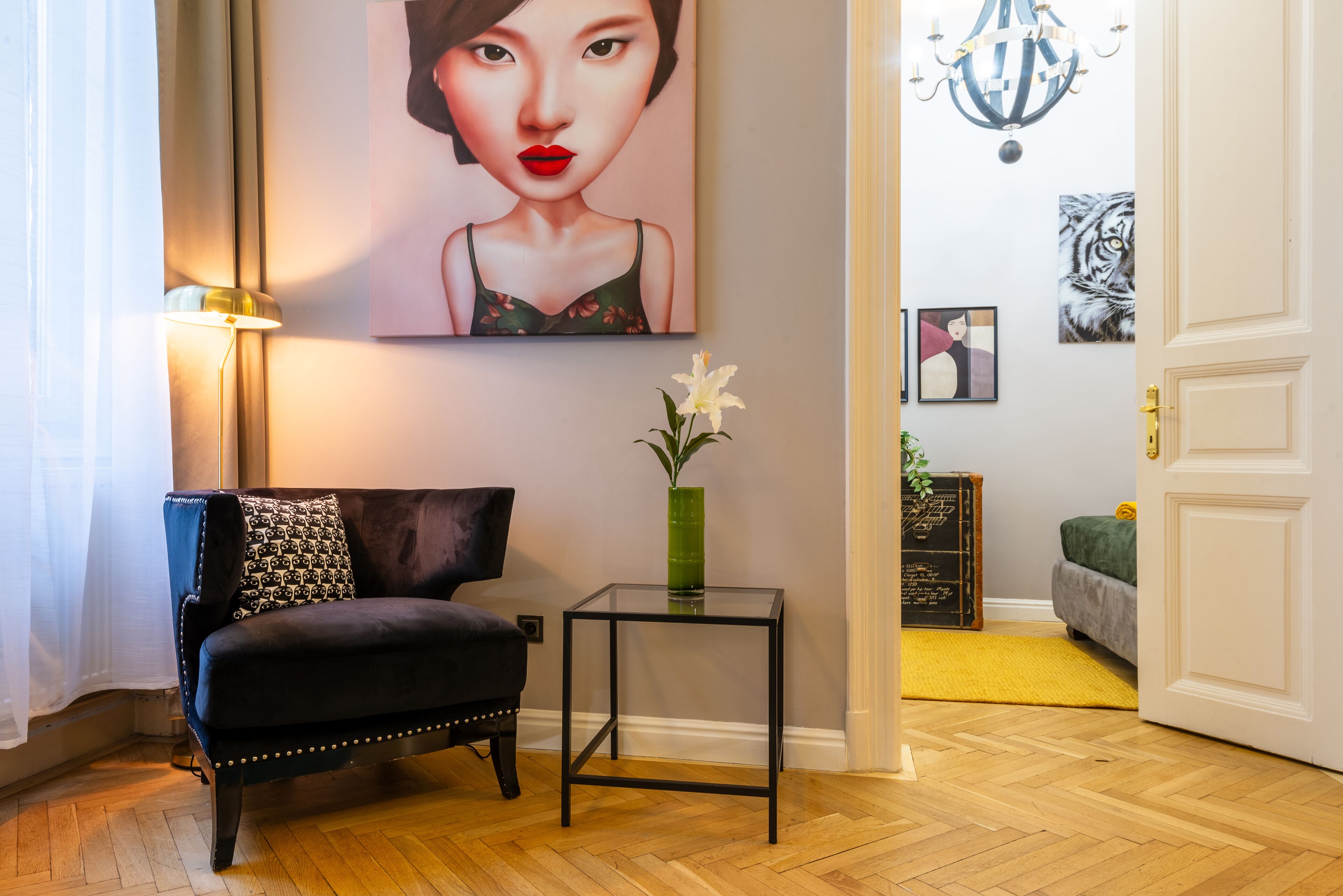 En stue med en sort sofa, et lille sofabord med en vase, og et billede på væggen.