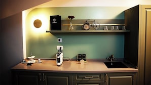 Uma cozinha com bancada, máquina de café, bicicleta e prateleiras com objetos.