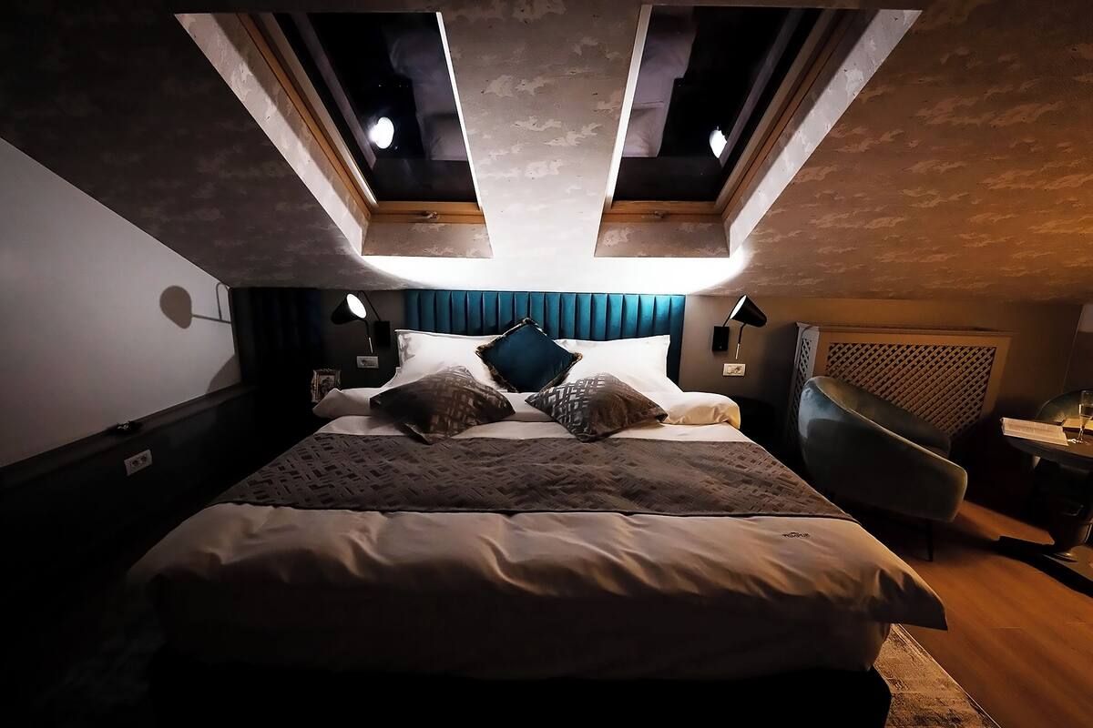A bedroom with a large bed, a headboard with a lattice design, and a skylight above.