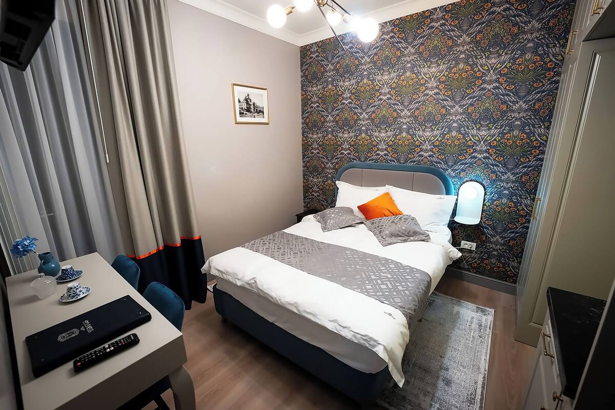 A neatly arranged bedroom with a bed, bedside table, and a desk with a chair.