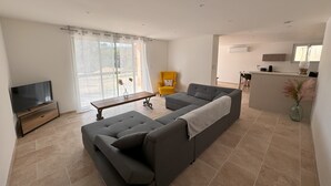A modern living room with a grey sofa, a yellow armchair, and a TV. - Gîte rdc Villa - Village Provençal - Proche Uzès (Le Pin)