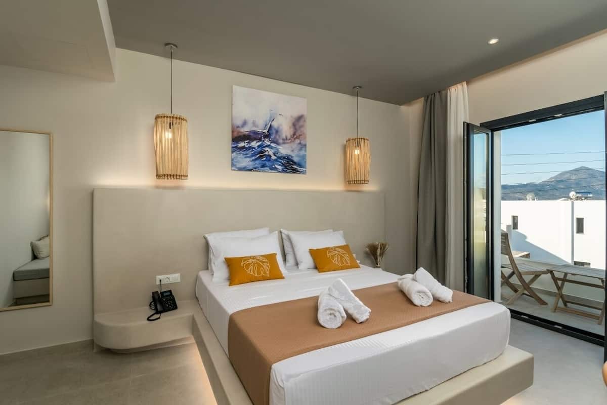 A modern hotel room with a large bed, a telephone, and a painting on the wall.