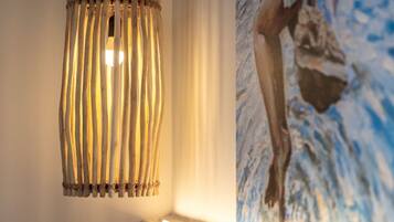 A wooden slatted pendant light fixture and a painting of a person in a blue and white abstract style.