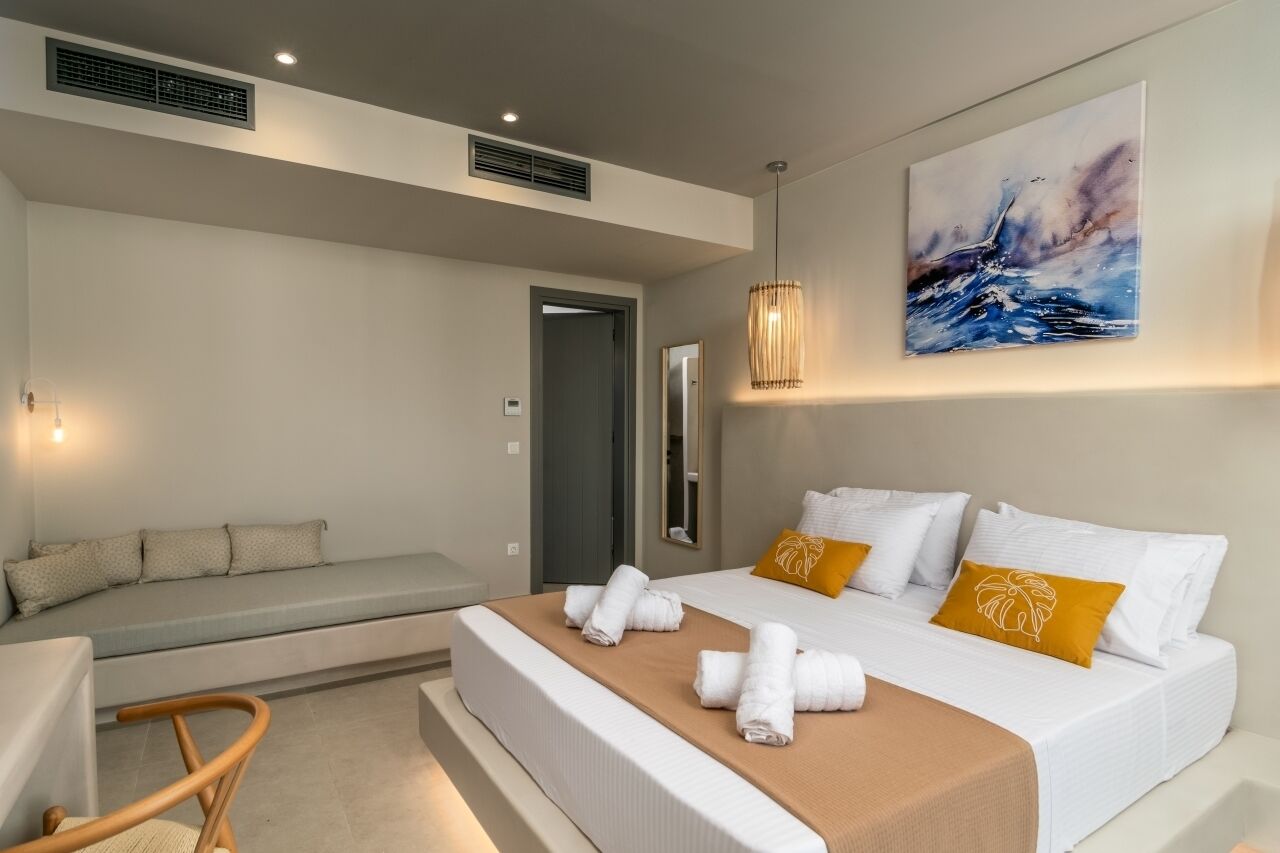 Ett modernt hotellrum med en stor säng, en sittgrupp och en tavla på väggen.