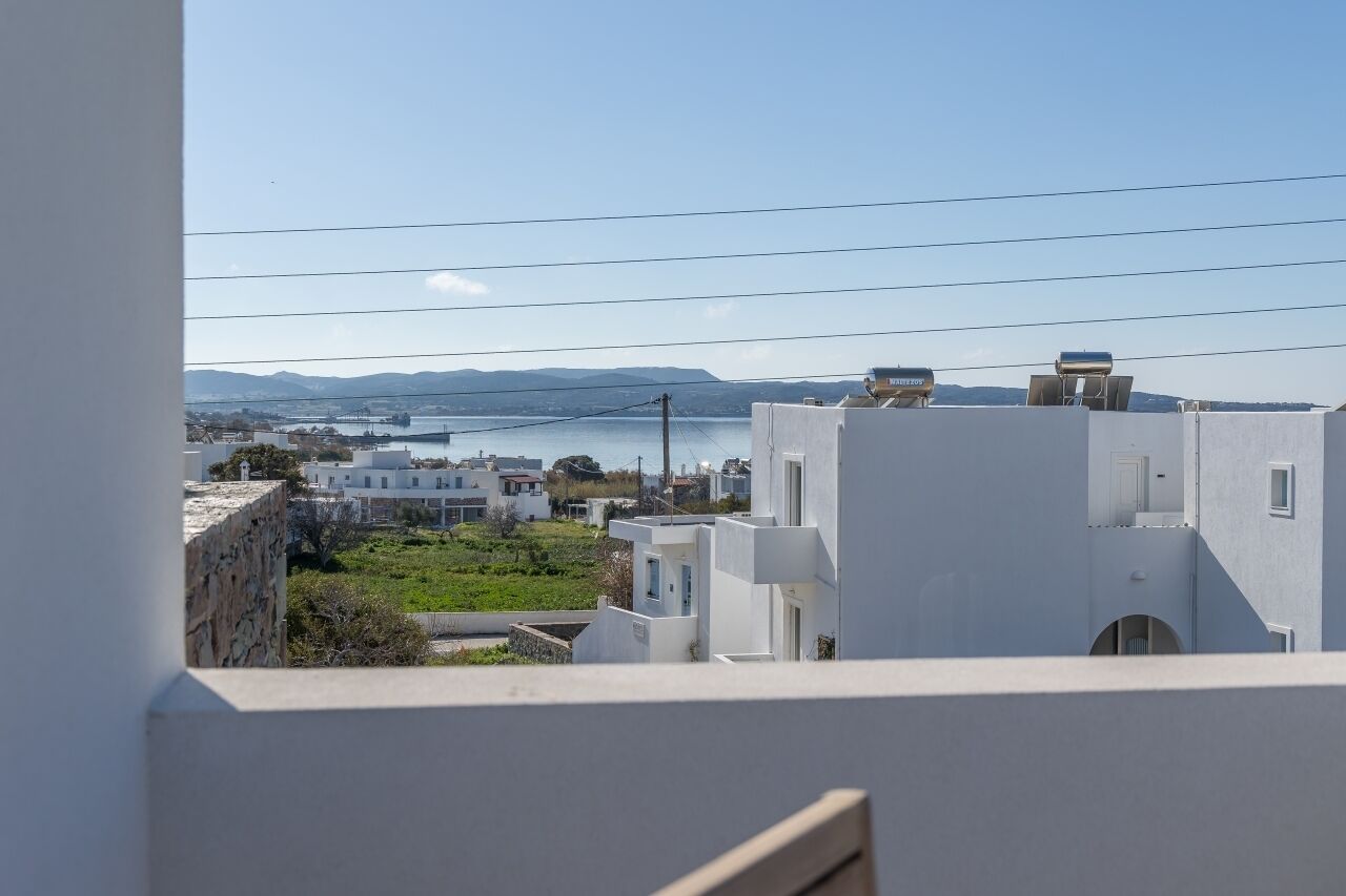 Vista di una cittadina costiera con edifici bianchi, cielo sereno e un tratto d'acqua all'orizzonte.