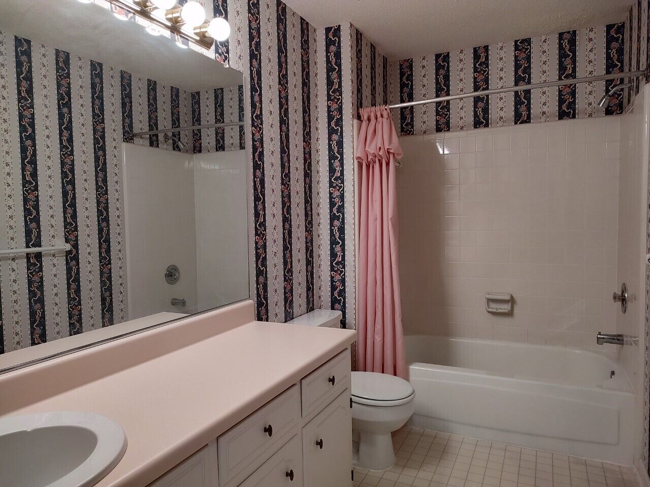 Une salle de bain avec une baignoire blanche, des toilettes et un lavabo doté d’un plan de toilette rose.