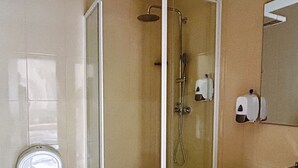 Un baño con inodoro, cabina de ducha y lavabo.