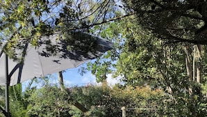 A garden with a table and chairs under a canopy, surrounded by greenery and trees. - Small independent 2-room flat (Cavalaire)
