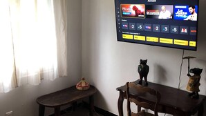 A room with a bed, a desk, and a television mounted on the wall displaying a movie channel. - Small independent 2-room flat (Cavalaire)