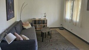 A living room with a sofa, a small table, a bookshelf, and a painting on the wall. - Small independent 2-room flat (Cavalaire)