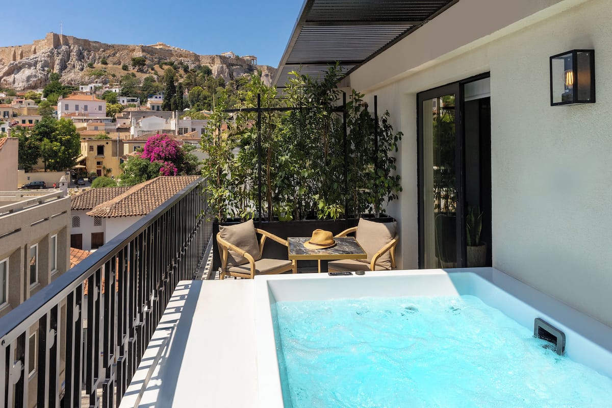 Un balcon doté d’un jacuzzi, d’un espace salon extérieur et offrant une vue sur une colline historique.
