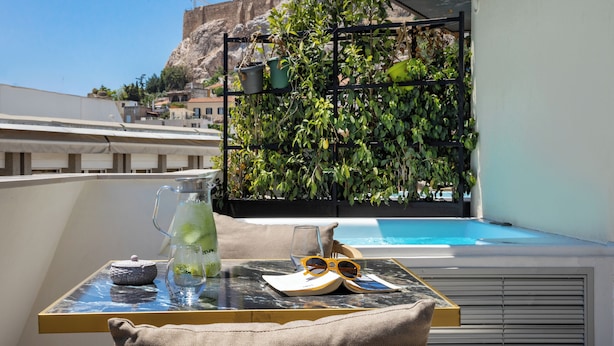 A balcony with a table, a potted plant, a drink, and a pair of sunglasses. - Esse Athens (Athens)