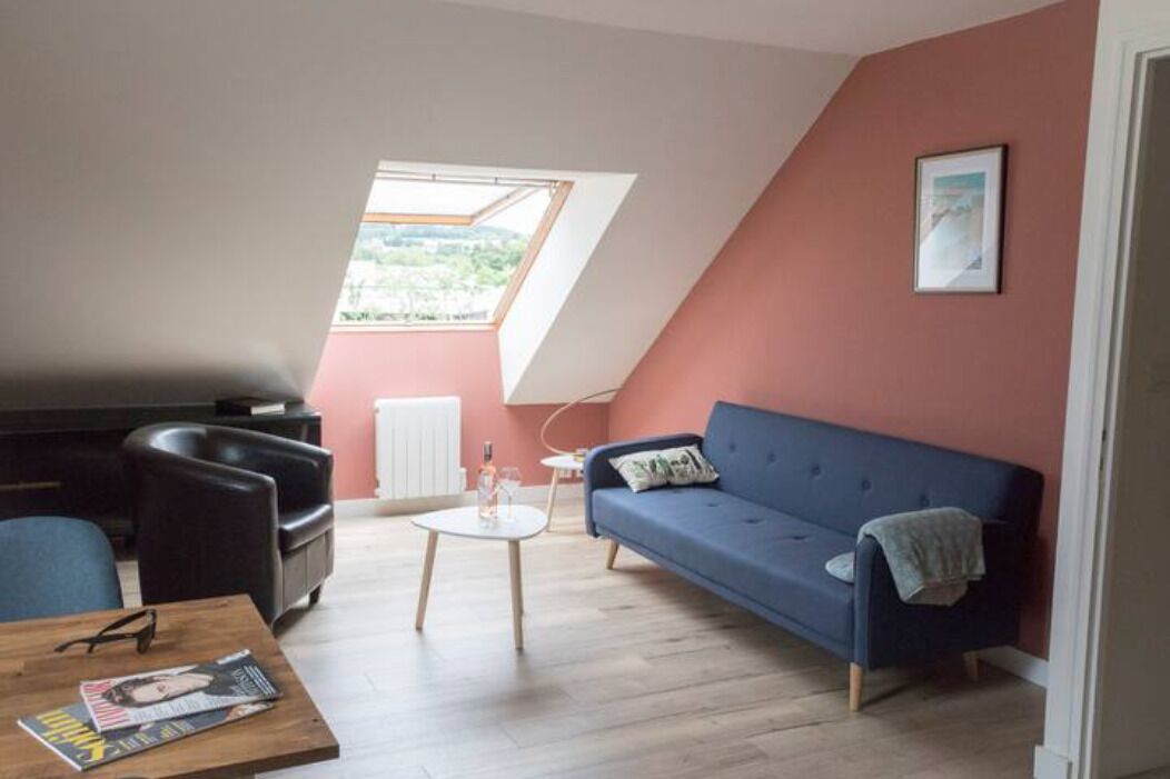 A cozy living room with a sloped ceiling, a blue sofa, a coffee table, and a view through a skylight.