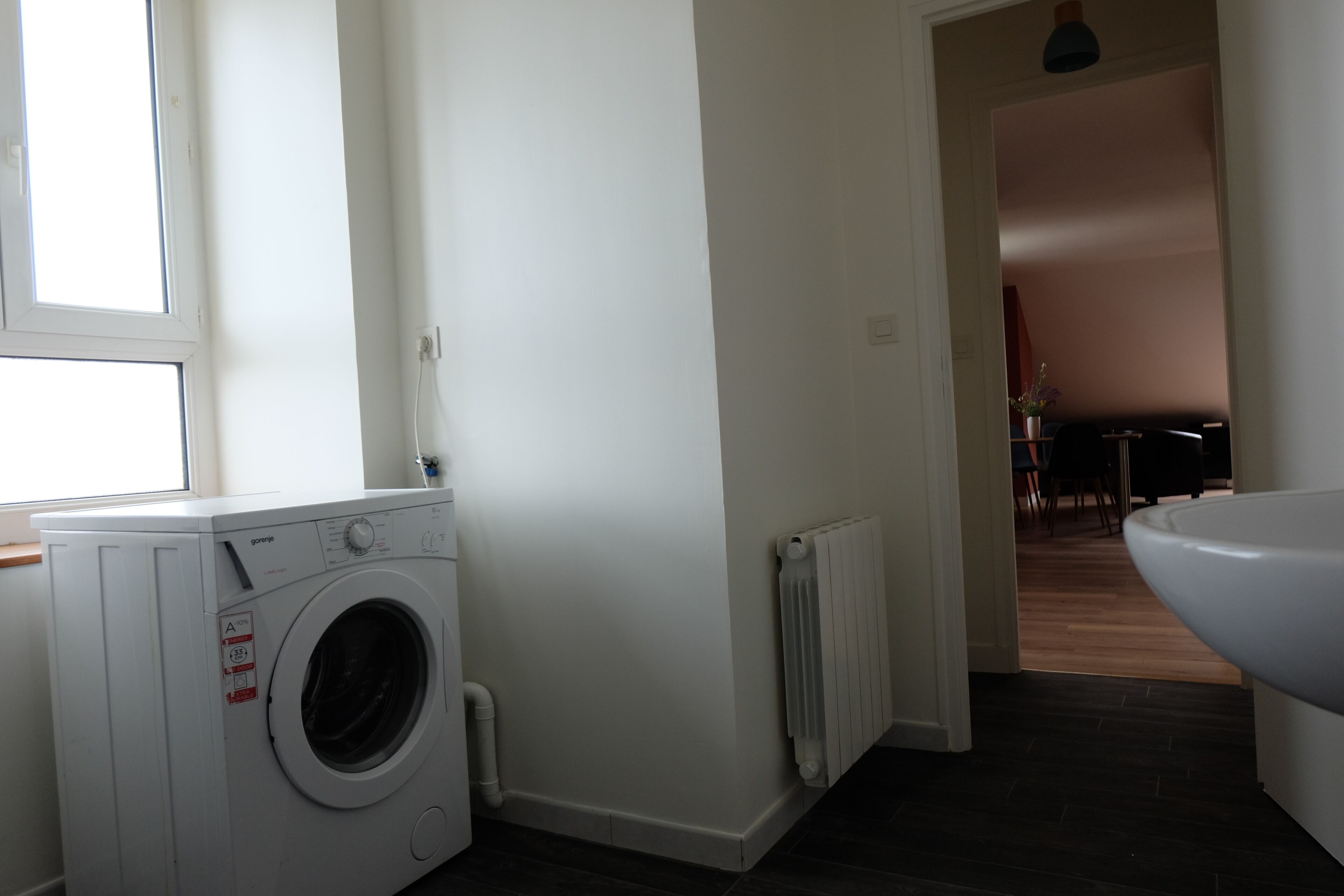 A laundry area with a washing machine, a radiator, and a sink.