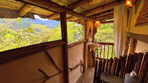 A wooden balcony with a view of lush greenery and mountains.
