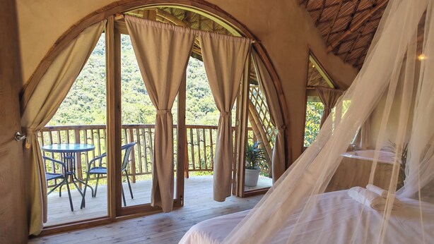 A bedroom with a bed, a small table, and chairs on a wooden deck.