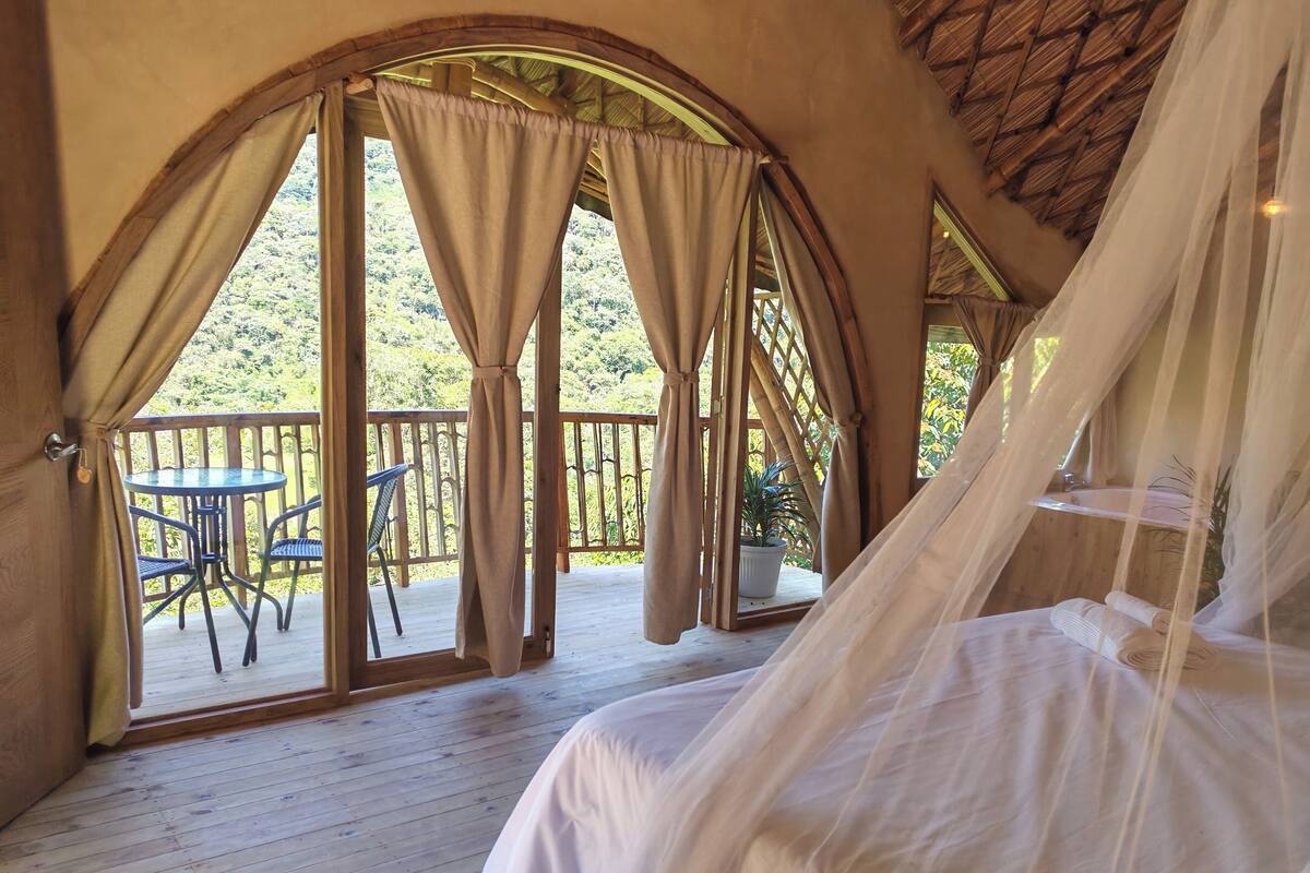 A bedroom with a bed, a small table, and chairs on a wooden deck.