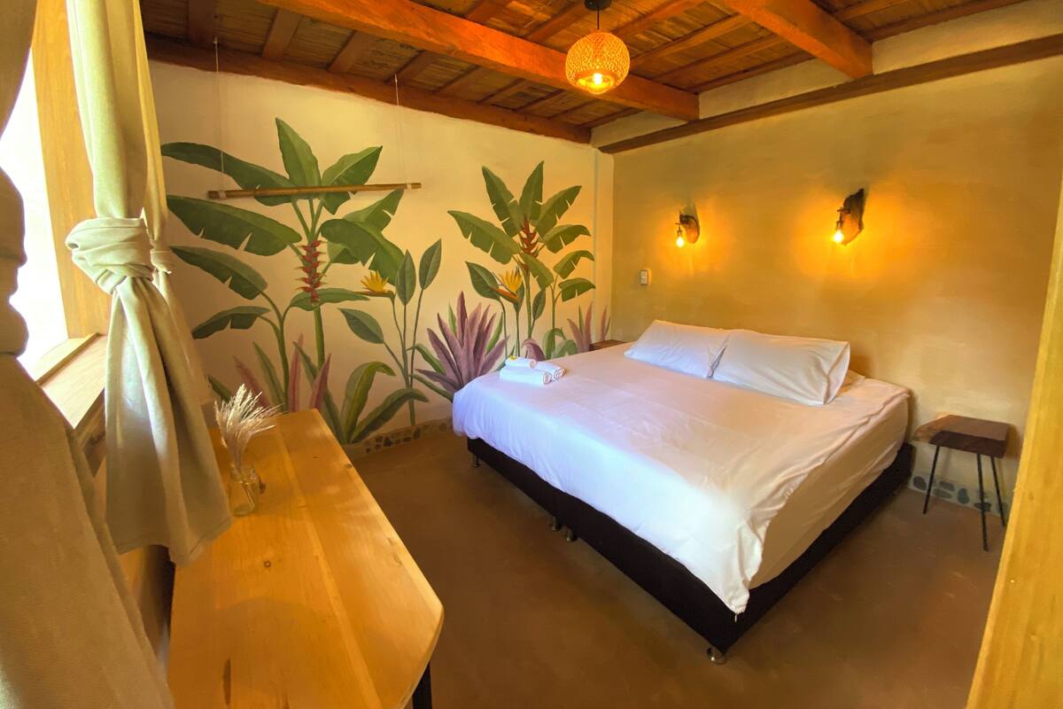 A bedroom with a bed, a wooden ceiling, a wall mural, and a nightstand.