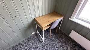 Una habitación de esquina con un escritorio de madera, una silla gris y un radiador.