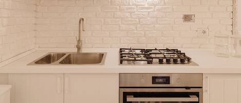 Uma cozinha moderna com armários brancos, uma pia de aço inoxidável e um fogão a gás.