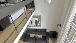 A modern loft-style living space with a loft bed, grey sofa, and a grey rug. - Saint Sebastian Flat 704Duplex no Centro (Jaragua do Sul)