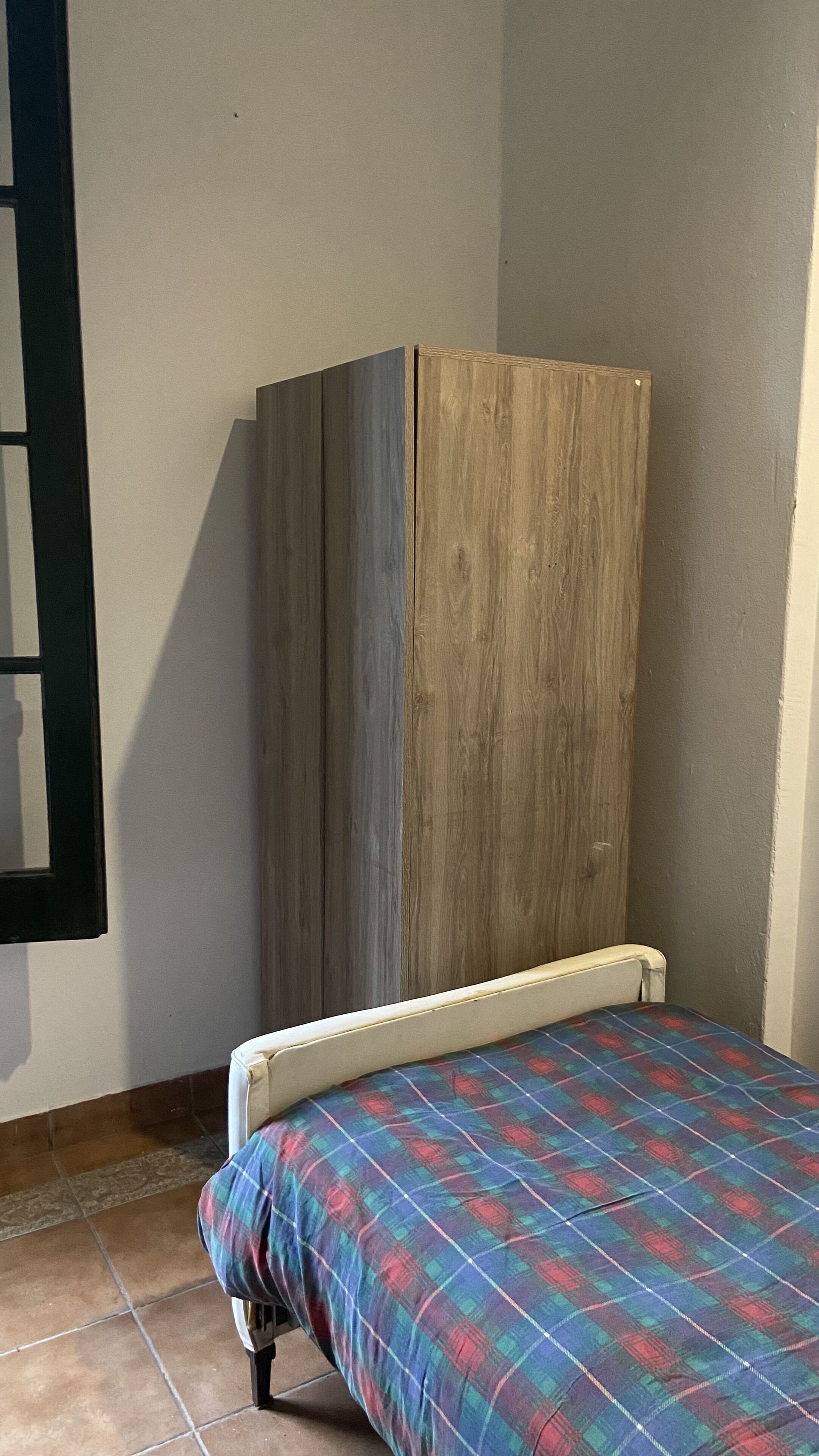 Une pièce avec un lit, une armoire et une fenêtre.