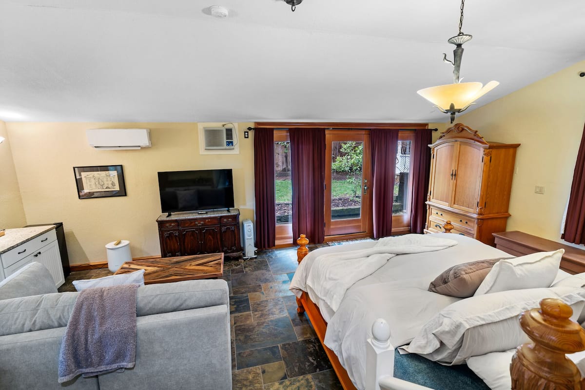 A bedroom with a bed, a desk, a television, and a wardrobe.