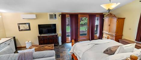 A bedroom with a bed, a desk, a television, and a wardrobe.