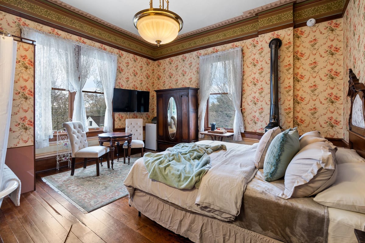A bedroom with a large bed, a desk, a chair, and a television.