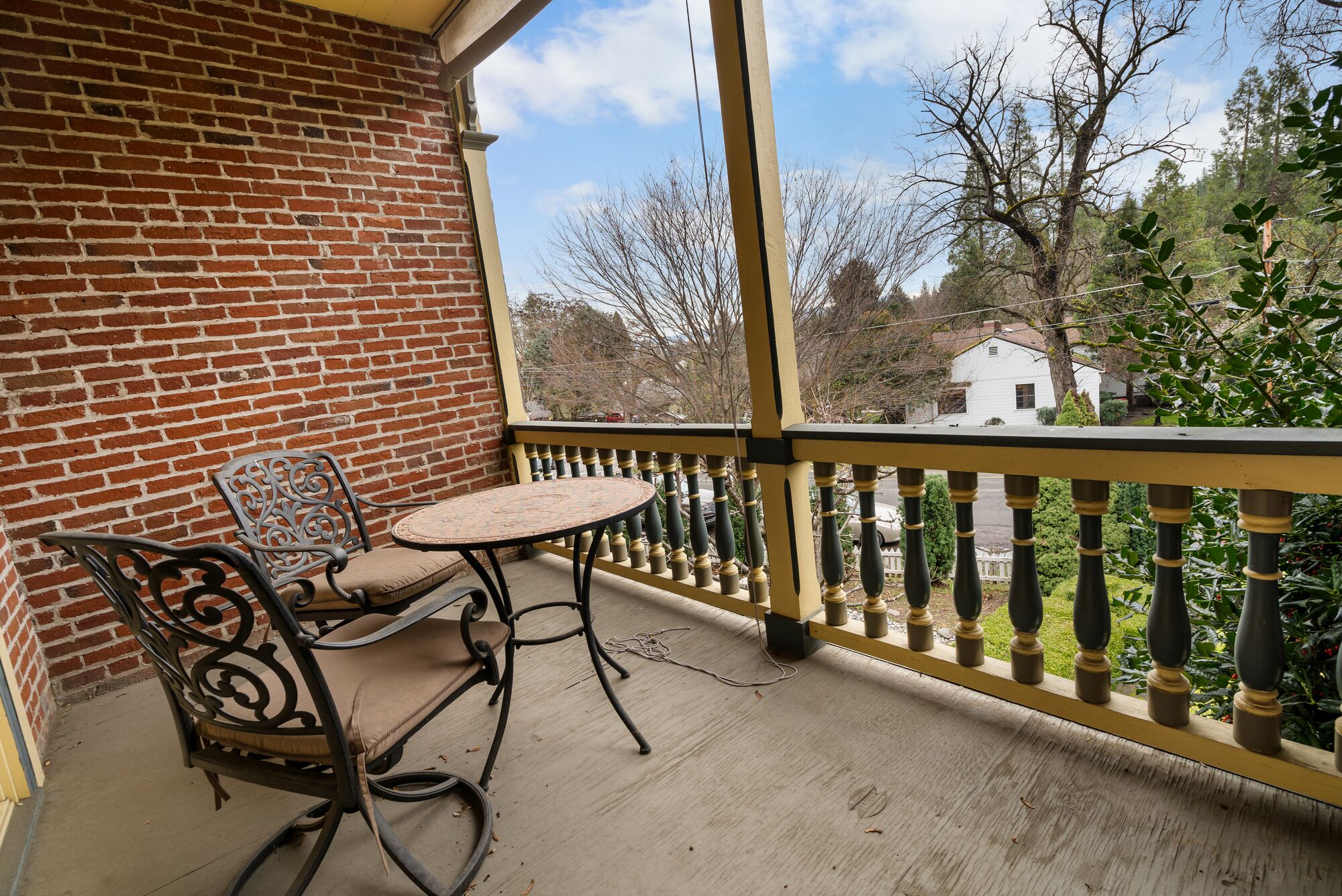 A balcony with a brick wall, a table, and two chairs.