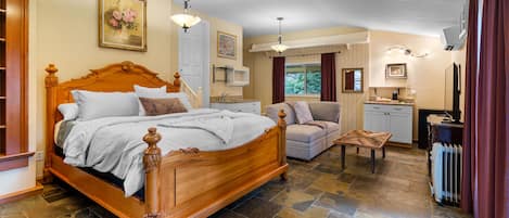 Ein Schlafzimmer mit einem hölzernen Bett, einer Sitzecke mit Tisch und einer Küchenzeile.