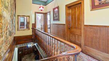 Un'imponente sala con una scala in legno, un lampadario e un grande quadro appeso al muro.