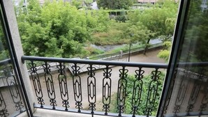 A balcony with a wrought iron railing overlooking a lush green park with trees and a small stream. - Alojamiento Caldas de Reis - Pensión (Caldas de Reis)