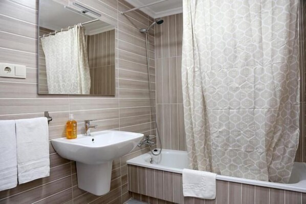 Un baño moderno con lavamanos, espejo y ducha.