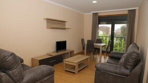 A modern living room with a sofa, a coffee table, a TV, and a balcony with a dining area. - Alojamiento Caldas de Reis - Pensión (Caldas de Reis)