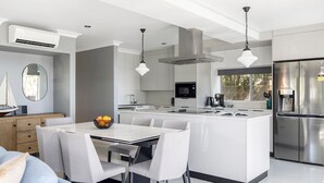 A modern kitchen with a central island, stainless steel appliances, and pendant lighting. - Spacious Woodlands Water Front Soldiers Point- Ground Floor Apartment (Soldiers Point)