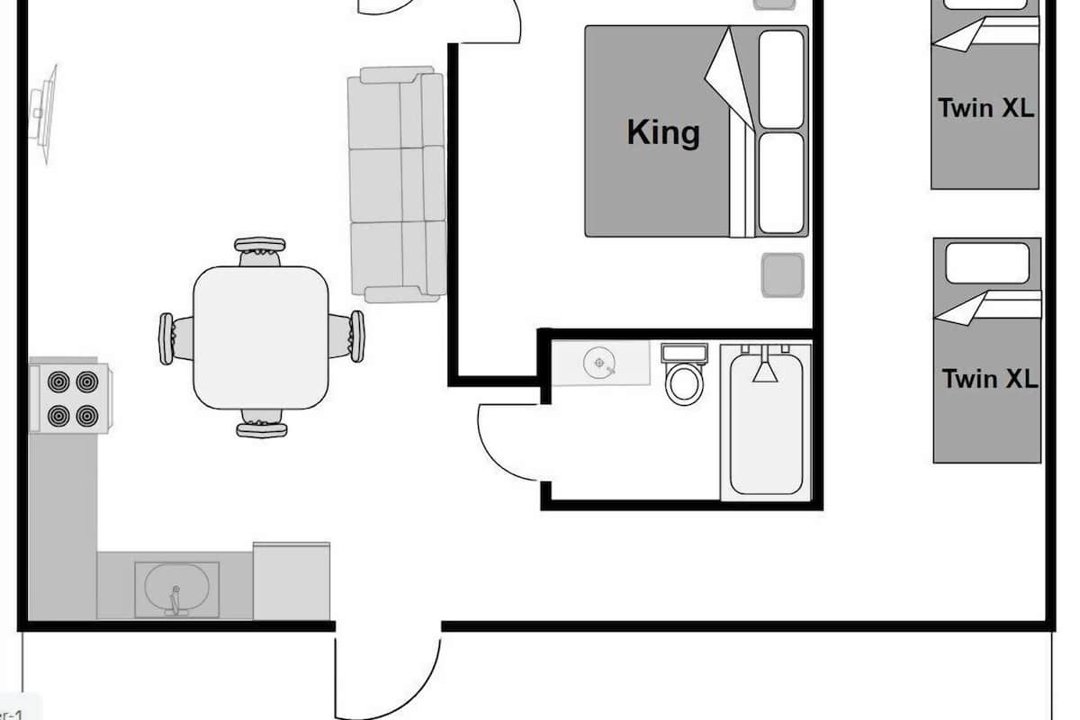 Plan d’étage d’une chambre d’hôtel comprenant un coin cuisine, un espace repas, une salle de bain et deux lits jumeaux de grande taille.