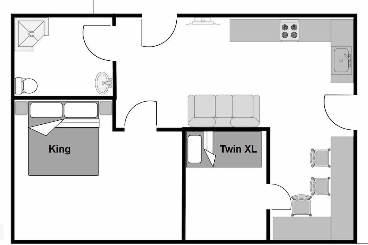 Un aménagement de chambre d’hôtel comprenant un lit « king size », un lit « twin XL », une kitchenette et une salle de bain.