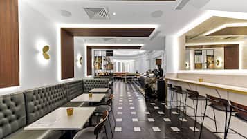 A modern restaurant with a long counter, cushioned seating, and a patterned floor.