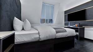 Een moderne slaapkamer met een bed, bureau en een grote televisie.
